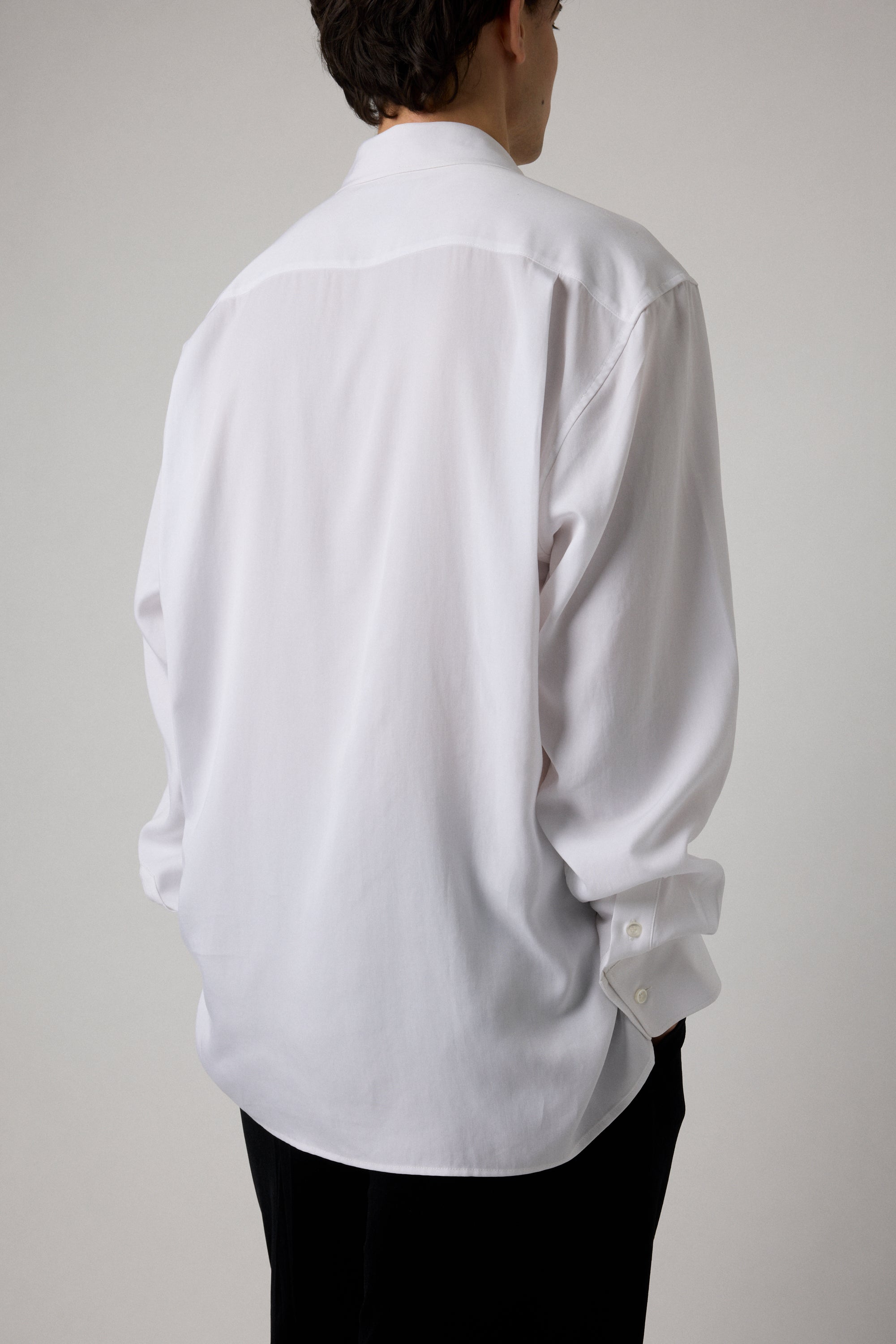 Person wearing a white dress shirt against a plain background