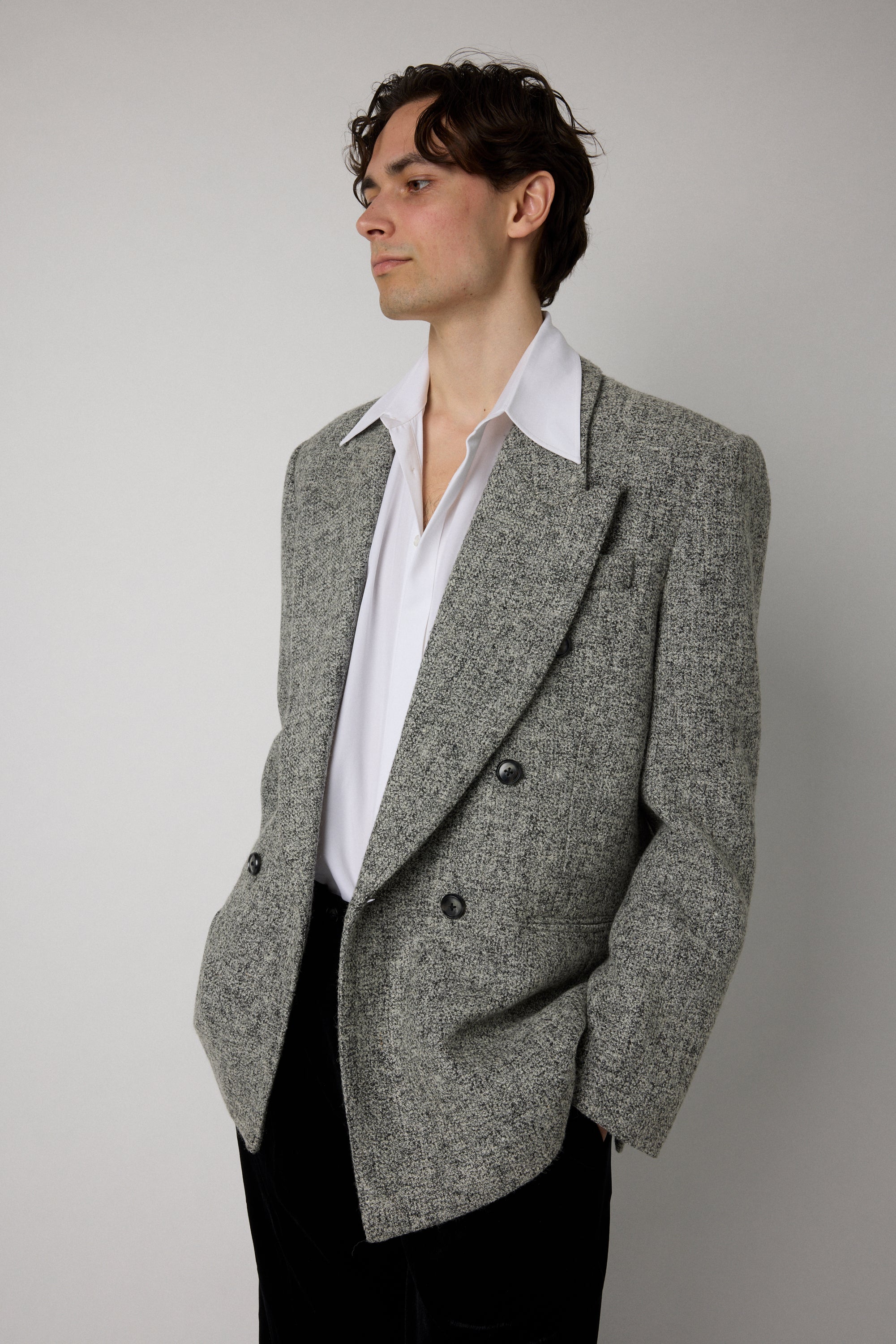 Man wearing a gray blazer over a white shirt on a plain background