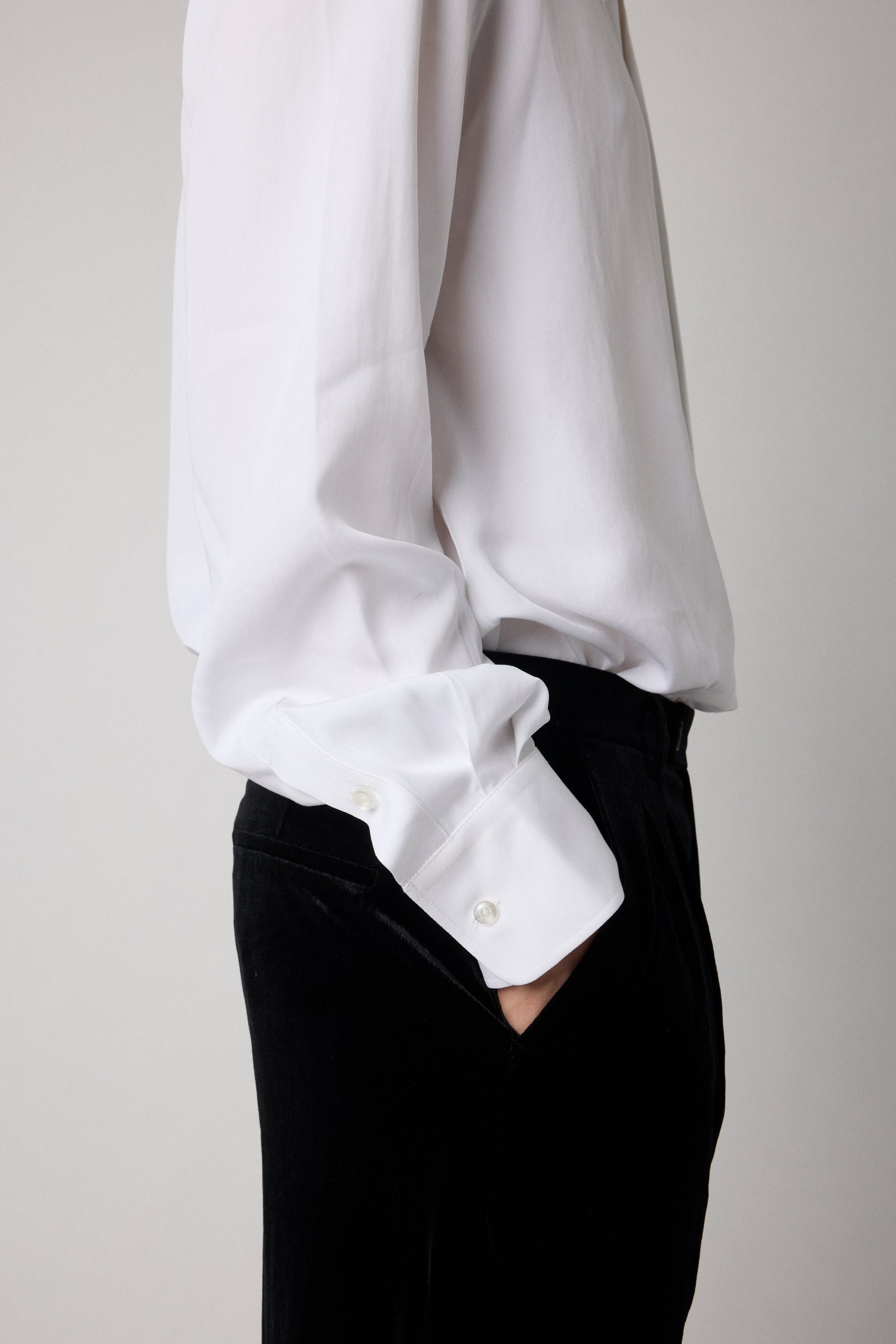 White shirt with rolled-up sleeves and black pants on a plain background